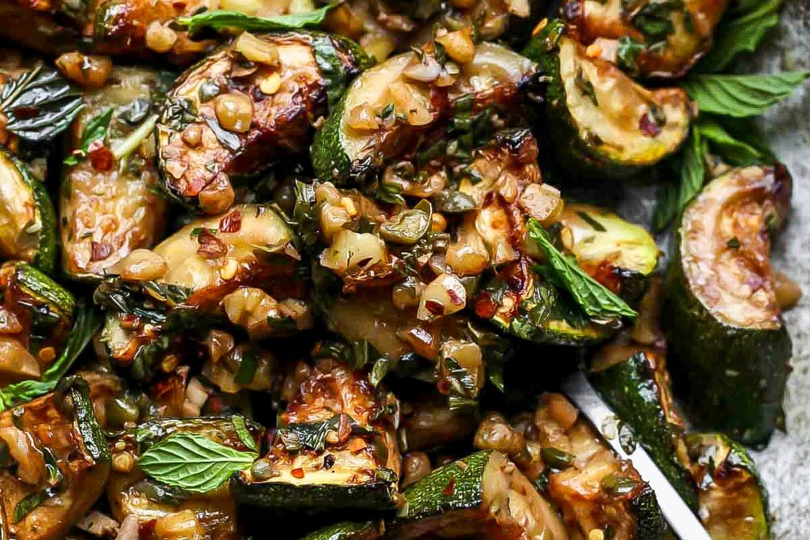 Pan-browned courgettes with garlic, capers, mint and chilli in a dark dish