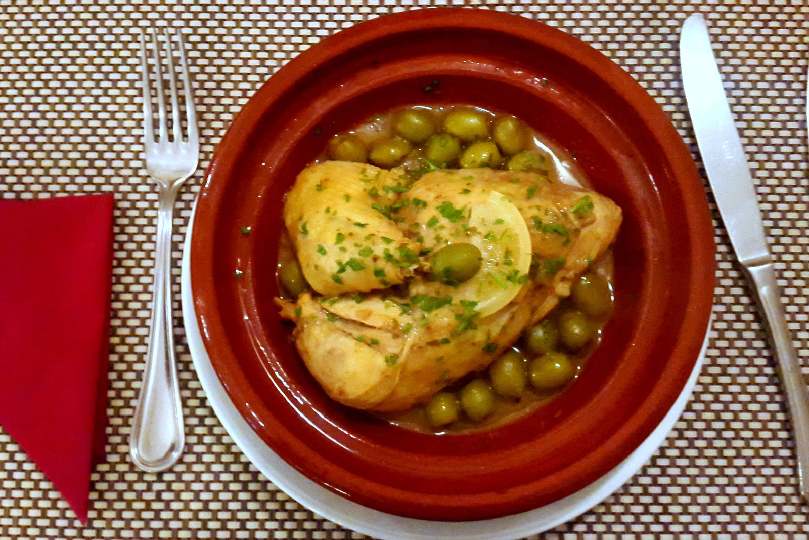 Chicken tagine with green olives and lemon in an earthenware dish