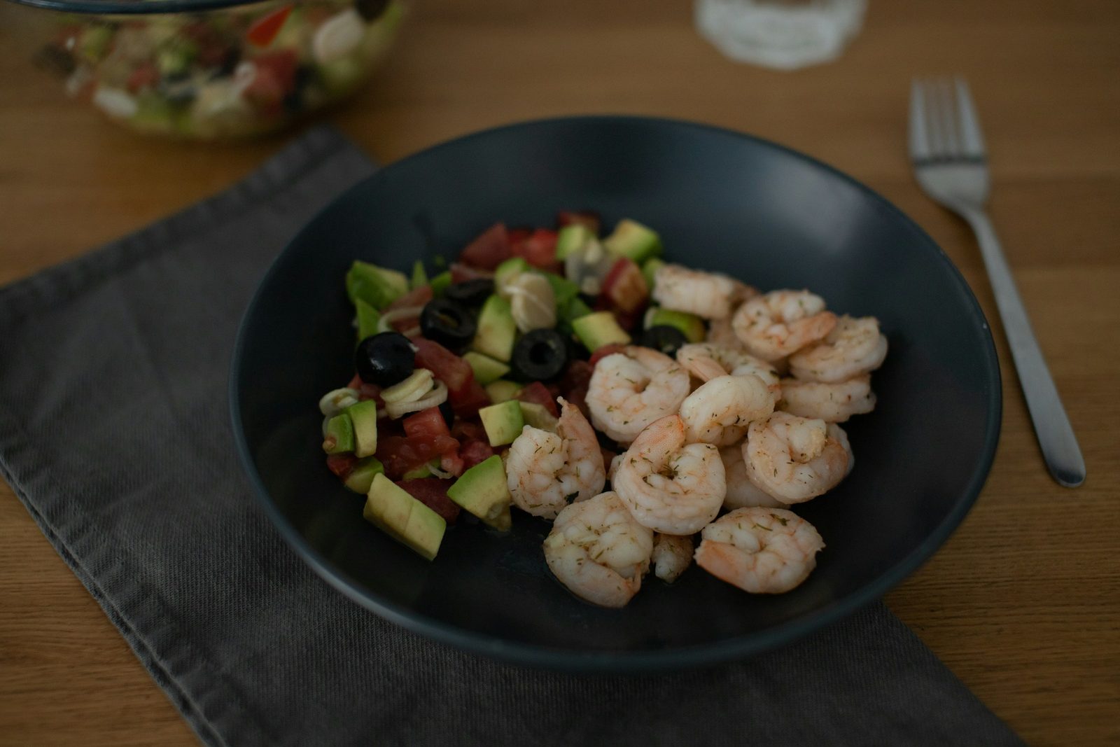 Prawns, avocado and tomatoes on a black plate