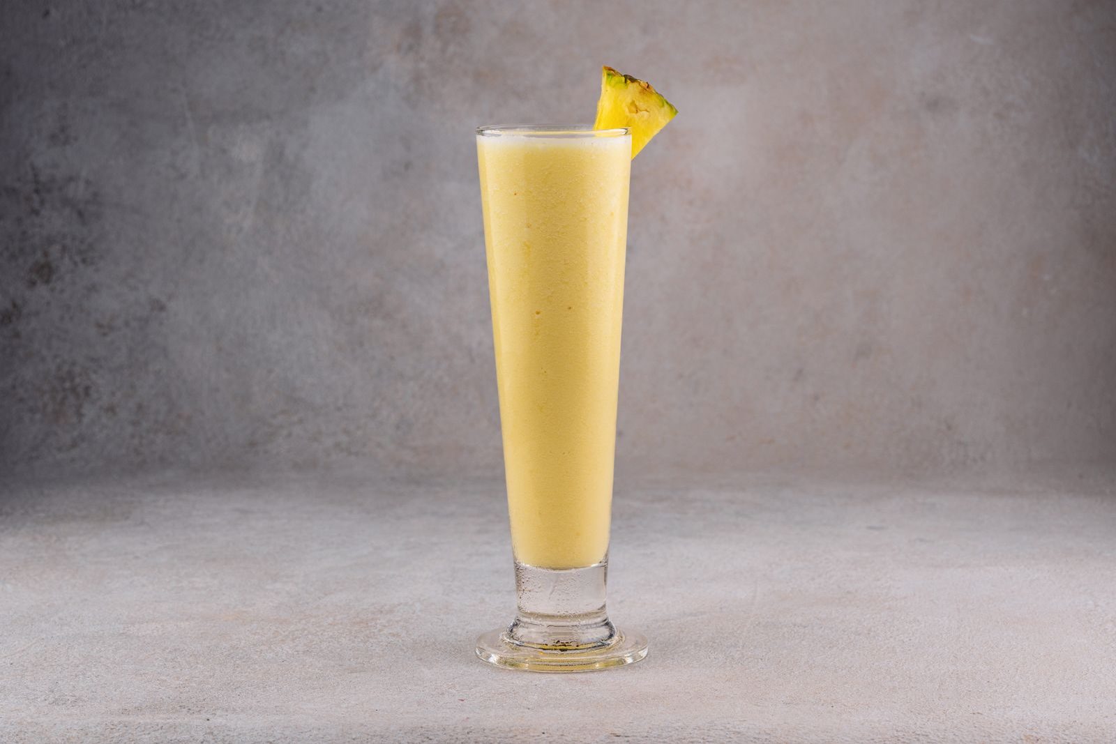 Yellow pineapple smoothie in a tall glass