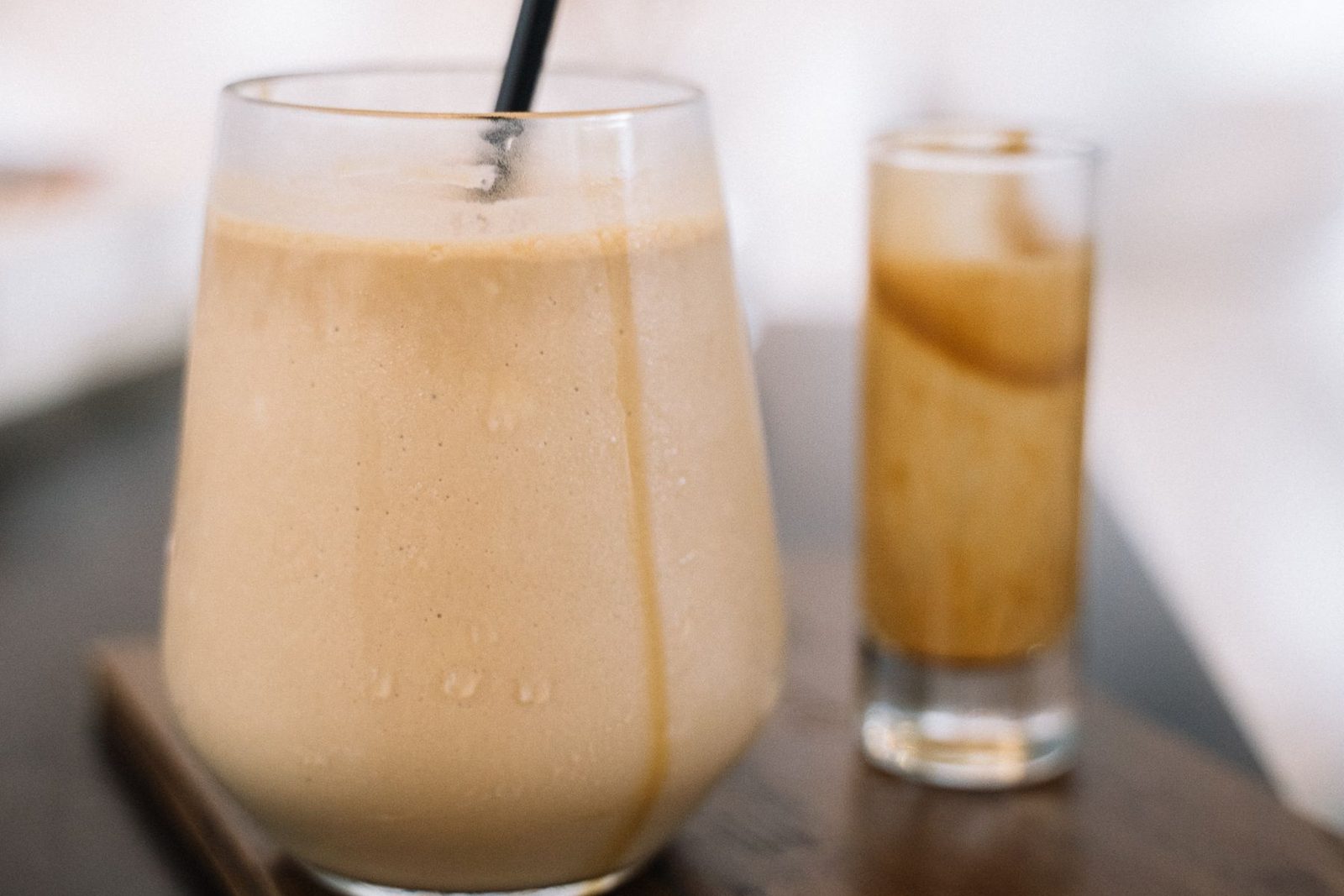 Coffee smoothie in a glass with a small glass of espresso beside it